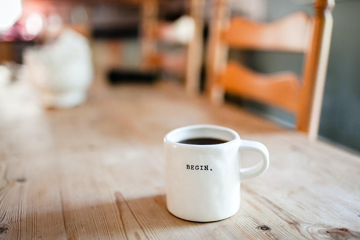 Coffee mug on wood table with the words begin on the cup